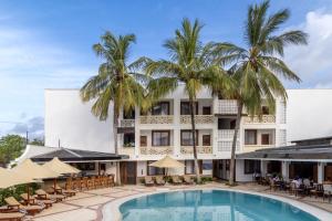 ein Hotel mit einem Pool und Palmen in der Unterkunft PrideInn Hotel Diani in Diani Beach