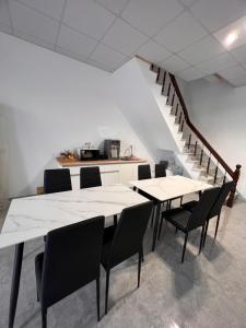 a dining room with white tables and chairs and a staircase at 茄萣路科民宿 