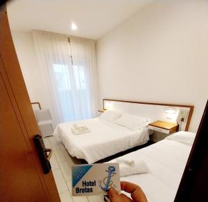 una persona in possesso di un libro in una camera d'albergo di Hotel Brotas a Rimini