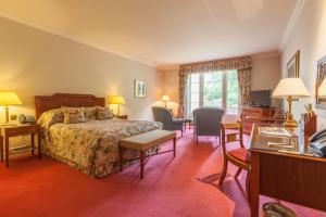 a hotel room with a bed and a desk and chairs at Luton Hoo Hotel, Golf and Spa in Luton