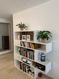 una estantería blanca con libros y macetas en Moderne Ferienwohnung in bester Lage!, en Bad Herrenalb