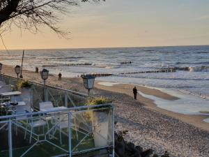 a beach with chairs and people walking on the beach at ART APARTAMENT MIELNO in Mielno