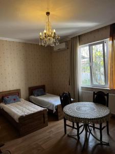 1 dormitorio con 2 camas, mesa y lámpara de araña en Papazo en Kutaisi