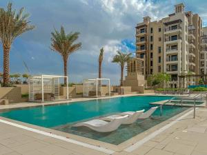 a swimming pool with white chairs and palm trees at HiGuests - Charming Modern Apartment Close To The Souk in MJL in Dubai