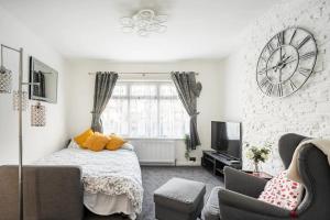 1 dormitorio con 1 cama y reloj grande en la pared en MOYDOM Cosy Apt sleeps 4 with self breakfast & carpark, en Redbridge