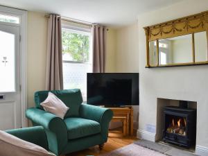 a living room with a green chair and a fireplace at The Nook in Thirsk