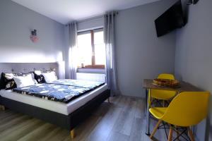 a bedroom with a bed and a table and yellow chairs at Noclegi Wiejski Raj in Chocieszow