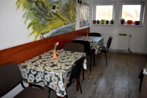 two tables and chairs in a restaurant with a painting at Penzión Ivana in Bardejov