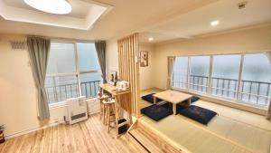 a room with a balcony with windows and a table at attomi hostel in Sapporo