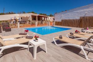 una piscina con tumbonas, una mesa y una piscina en VillaBlanca en Sant Rafael