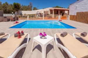a pool with two chairs and a table with flowers on it at VillaBlanca in Sant Rafael