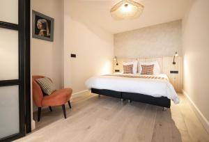 um quarto com uma cama grande e uma cadeira em Four Star Apartments - Badhuisstraat 6 em Scheveningen