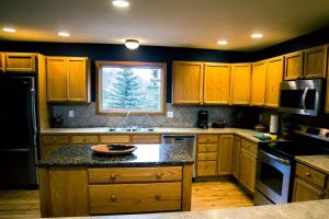 cocina con armarios de madera, fregadero y ventana en Virginia Home by Rocky Mountain Resorts- #3106, en Estes Park