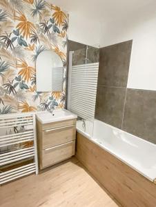 łazienka z wanną, umywalką i lustrem w obiekcie Joli appartement hyper-centre w mieście Alençon