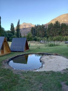 a small pond in a field with a tent at Hostel Chacra La Templanza in El Hoyo