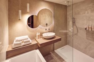 een badkamer met een wastafel, een bad en een spiegel bij Van der Valk Hotel Gorinchem in Gorinchem