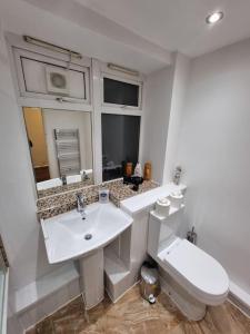 Baño blanco con lavabo y aseo en Cosy 3 bed Apt/contractors/families/free parking, en Birmingham