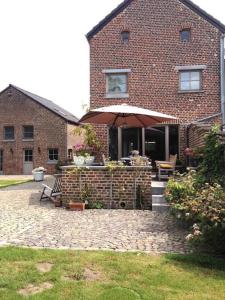 a brick house with an umbrella in front of it at Country house Clos des hortensias in Blégny