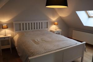 Country house Clos des hortensias في Blégny: غرفة نوم بسرير ابيض مع طاولتين ونافذة