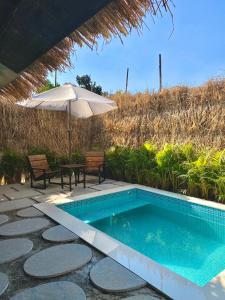羅納瓦拉的住宿－ROOM with PRIVATE POOL BY CANVAS VILLA LONAVLA，一个带遮阳伞和桌椅的游泳池