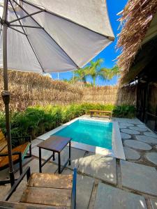 ROOM with PRIVATE POOL BY CANVAS VILLA LONAVLA في لونافالا: مسبح مع مظلة وطاولة وكرسي