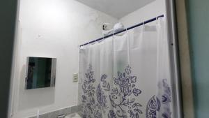 La salle de bains est pourvue d'une douche avec un rideau de douche bleu et blanc. dans l'établissement A Pousada., à Barra dos Coqueiros
