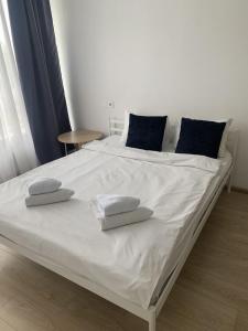 uma cama grande com lençóis brancos e almofadas azuis em Nyvky like Home em Kiev