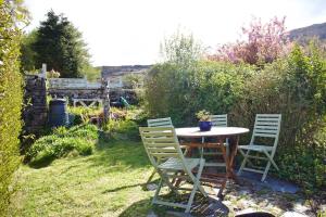 a table and four chairs in a garden at Cosy cottage with mountain views in Blaenau-Ffestiniog