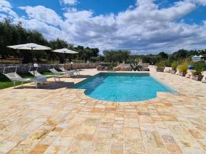 a swimming pool with two chairs and an umbrella at Quattroperle Trulli - Relax - Puglia in Castellana Grotte
