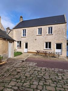 una casa de piedra con un banco delante en Gite des falaises de Longues 8personnes, en Longues-sur-Mer