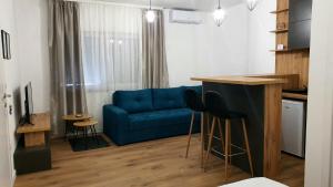 a living room with a blue couch and a kitchen at Apartman Campari in Banja Luka