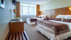 a hotel room with two beds and a bench at HOTEL EL DORADO in Concepción