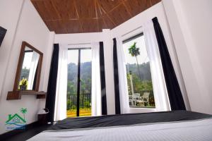 a bedroom with a bed and windows with a view at ACH RIVER RESORT in Rattota