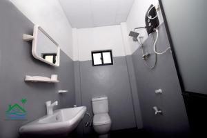 een badkamer met een wastafel, een toilet en een douche bij ACH RIVER RESORT in Rattota