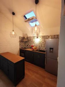 - une cuisine avec des armoires noires et un réfrigérateur dans l'établissement Le loft jeanne, à Orléans