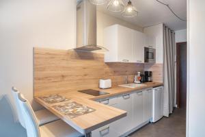 a kitchen with white cabinets and a wooden counter top at Kersalé in Bénodet