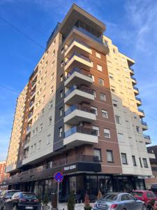 a tall building with cars parked in front of it at Apartman Ano LUX in Novi Pazar