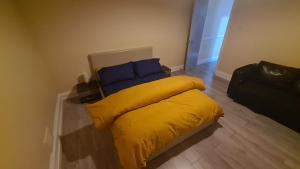 a yellow bed with blue pillows in a room at Entire 2 Bedroom Home/Flat In London, Central Line in London
