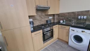 a kitchen with a stove top oven next to a washing machine at Entire 2 Bedroom Home/Flat In London, Central Line in London