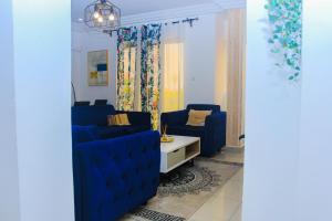 een woonkamer met twee blauwe stoelen en een tafel bij Appartement cosy blue bonapriso in Douala