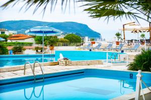 a swimming pool with chairs and an umbrella at Hotel Numana Palace in Numana