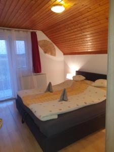 a large bed in a room with a wooden ceiling at Vilmos Pince Fogadó in Hévíz