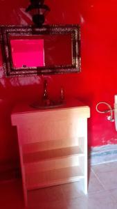 a red bathroom with a sink and a mirror at Oasis enchantée in Merzouga
