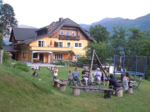 un grupo de personas sentadas en una mesa de picnic frente a una casa en Ferienwohnung Freihof - Nassfeld, en Hermagor
