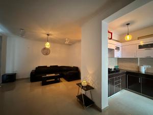 a living room with a black couch and a kitchen at Villa Vista With Swimming Pool in Lucknow