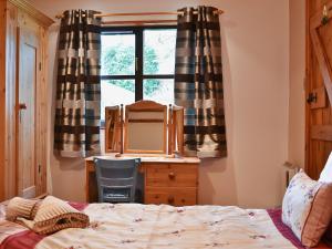 a bedroom with a bed and a desk and a window at Dan Y Faen in Devils Bridge