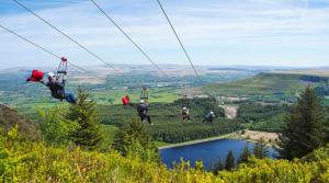 a group of people riding on a zip line over a lake at Gorgeous comfortable Apartment on the High Street in Merthyr Tydfil