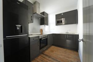 a kitchen with black cabinets and stainless steel appliances at Gorgeous comfortable Apartment on the High Street in Merthyr Tydfil