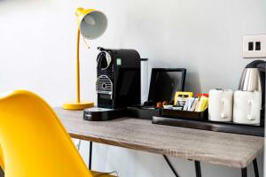 a desk with a coffee maker and a yellow chair at Heeton Concept Hotel - Kensington London in London