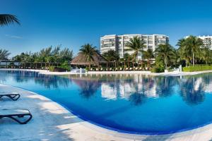 a large swimming pool with palm trees and buildings at Amara, depa con vista al mar in Cancún